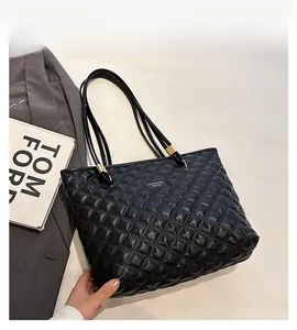 Detail view of black quilted tote bag with glossy leather finish and gold metal accents