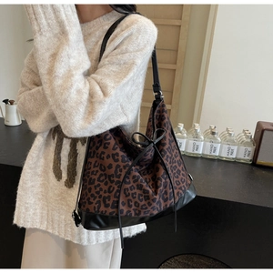 Detail of leopard print tote bag with black leather patchwork and bow tie accent