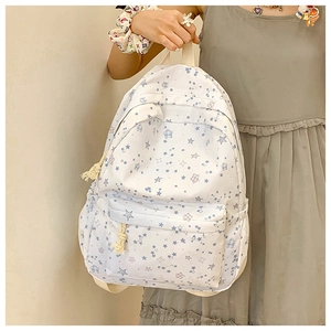 Detailed view of white canvas backpack with blue star patterns worn by a model