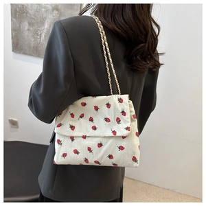 Detail view of cream corduroy crossbody bag with strawberry floral print and gold chain