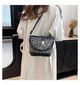 Detail of leopard print bucket bag with gold hardware and black leather trim on model