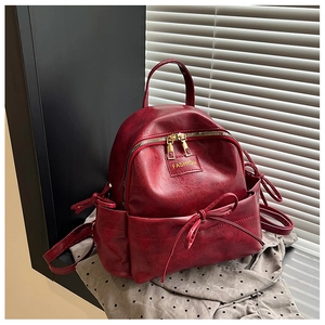 Vue détaillée de la texture en cuir synthétique bordeaux et du nœud sur le sac à dos