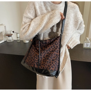 Detailed view of the leopard print canvas crossbody bag styled with a vintage sweater