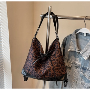 Detailed view of leopard print canvas tote bag with black leather straps and a bow