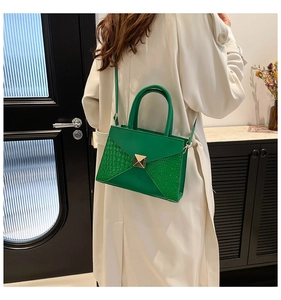 Detail showing emerald green envelope bag with crocodile texture and gold buckle detail