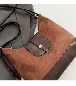 Detailed close-up of brown patchwork tote bag with suede texture and metal buckle