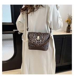 Modern leopard print bucket bag with leather trim and gold buckle shown on a model