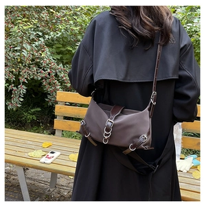 Détail d'un sac à bandoulière rétro marron foncé avec lanières en cuir sur un mannequin
