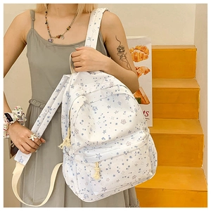 Detailed view of white student backpack with blue star patterns and front zip pocket