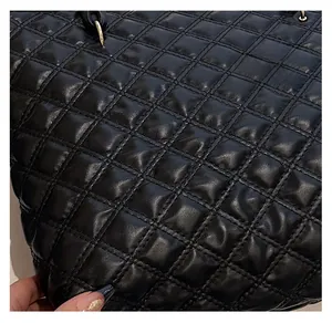 Close-up of the black quilted leather texture and premium stitching details on the tote bag