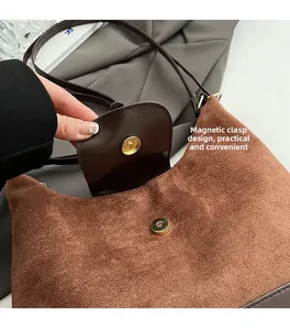 Detail of a brown suede tote bag featuring a circular magnetic snap closure design