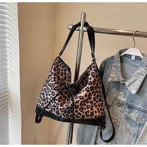 Detail view of large leopard print tote bag with black bow hanging near denim jacket