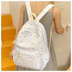 Detail of white canvas student backpack with blue star patterns and spacious front pocket