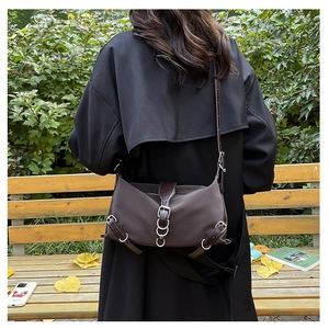 Détail du sac bandoulière marron foncé avec anneau métallique porté à l'épaule