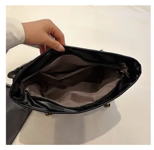 Internal view of black tote bag showing spacious brown lining with zipper pockets