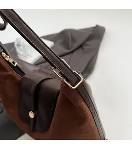 Close-up of brown leather and suede stitching detail with premium gold hardware accents