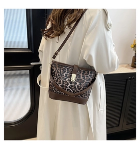 Detailed side view of leopard print bucket bag with brown leather strap and gold buckle