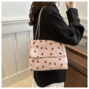 Pink corduroy shoulder bag with strawberry embroidery and a woven chain strap