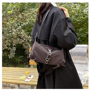 Détail d'un sac à bandoulière rétro marron foncé avec boucles en métal sur un banc