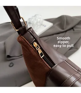 Close-up of smooth gold zipper and premium brown leather and suede textures on a tote bag