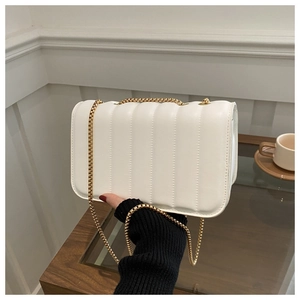 Close-up of white quilted crossbody bag with vertical texture and gold chain strap