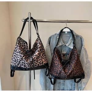 Detail view of leopard print tote bags in two colors hanging on a metal stand