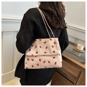 Pink corduroy crossbody bag with strawberry pattern and gold chain strap on model
