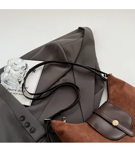 Detail of a brown suede hobo bag with dark leather strap and golden metal buckle