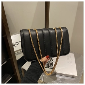 Detail of black vertical quilted leather bag with elegant golden chain strap