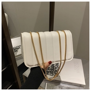 Detailed view of the vertical quilted texture and gold chain on the white shoulder bag