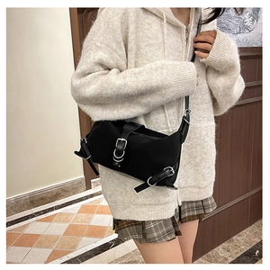 Détail du sac à bandoulière noir avec boucles en métal argenté et style punk moderne