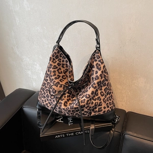 Leopard print tote bag with black bow detail and leather handles on a vintage book