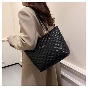 Close-up of black quilted tote bag with glossy finish and gold buckle detail