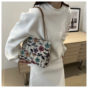 Detail of floral corduroy shoulder bag with gold chain strap on a white sweatshirt
