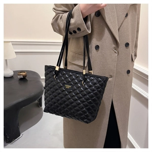 Detail of black quilted tote bag with gold hardware and fashion bags logo label