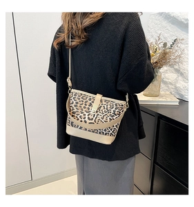 Detail view of leopard print crossbody bag with beige leather trim and gold metal clasp