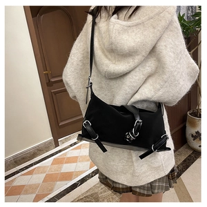 Détail d'un sac bandoulière en nylon noir avec des boucles en métal argenté