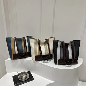Three striped canvas tote bags in blue, beige, and black with brown leather handles