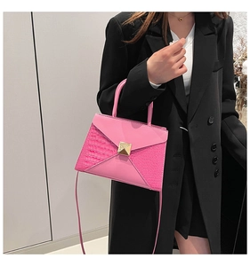 Detail of pink crossbody bag with crocodile texture and gold square rivet accent