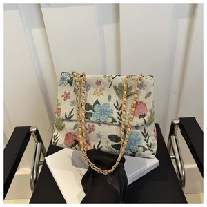 Detailed view of the floral woven texture and gold chain strap on the crossbody bag