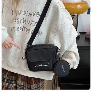 Detail of black nylon crossbody bag with matching round coin purse and white text