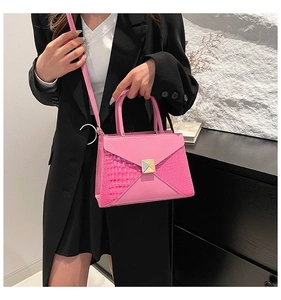 Detail view of a pink envelope handbag with crocodile embossed leather and a gold square buckle