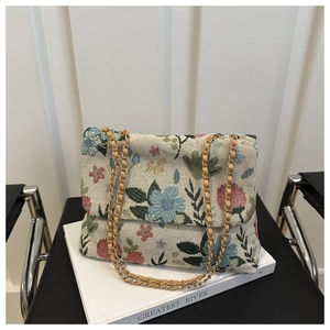 Close-up of floral jacquard texture and metal chain strap on vintage corduroy crossbody bag