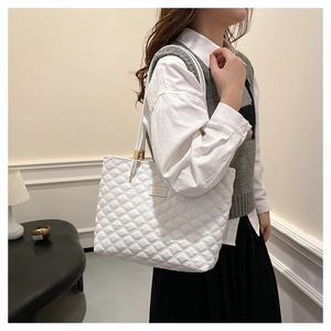 Close-up of white quilted tote bag texture featuring detailed stitching and metal buckle
