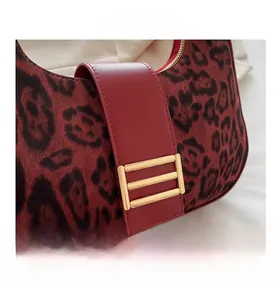 Detalle del bolso de ante con estampado de leopardo, correa de cuero rojo y hebilla dorada