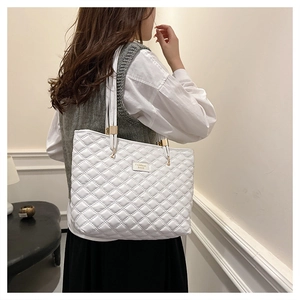 Detail of white quilted tote bag with golden metal hardware and fashion logo