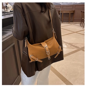 Détail d'un sac bandoulière rétro caramel avec boucles argentées sur cuir synthétique