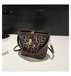 Close-up of leopard print bucket bag featuring a gold metal buckle and brown leather trim