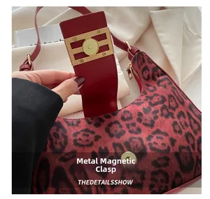 Primer plano del cierre magnético dorado en el bolso de ante con estampado de leopardo rojo