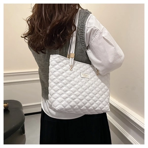 Detail view of white quilted tote bag with gold hardware and elegant diamond stitching